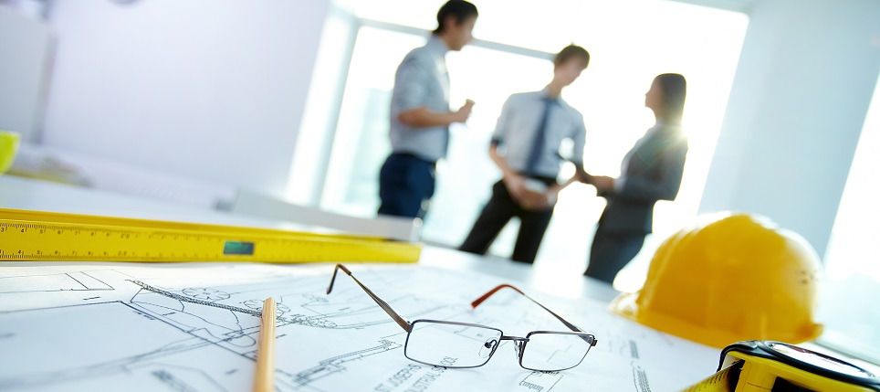 Planunterlagen, Bauhelm und Werkzeuge auf einem Besprechungstisch